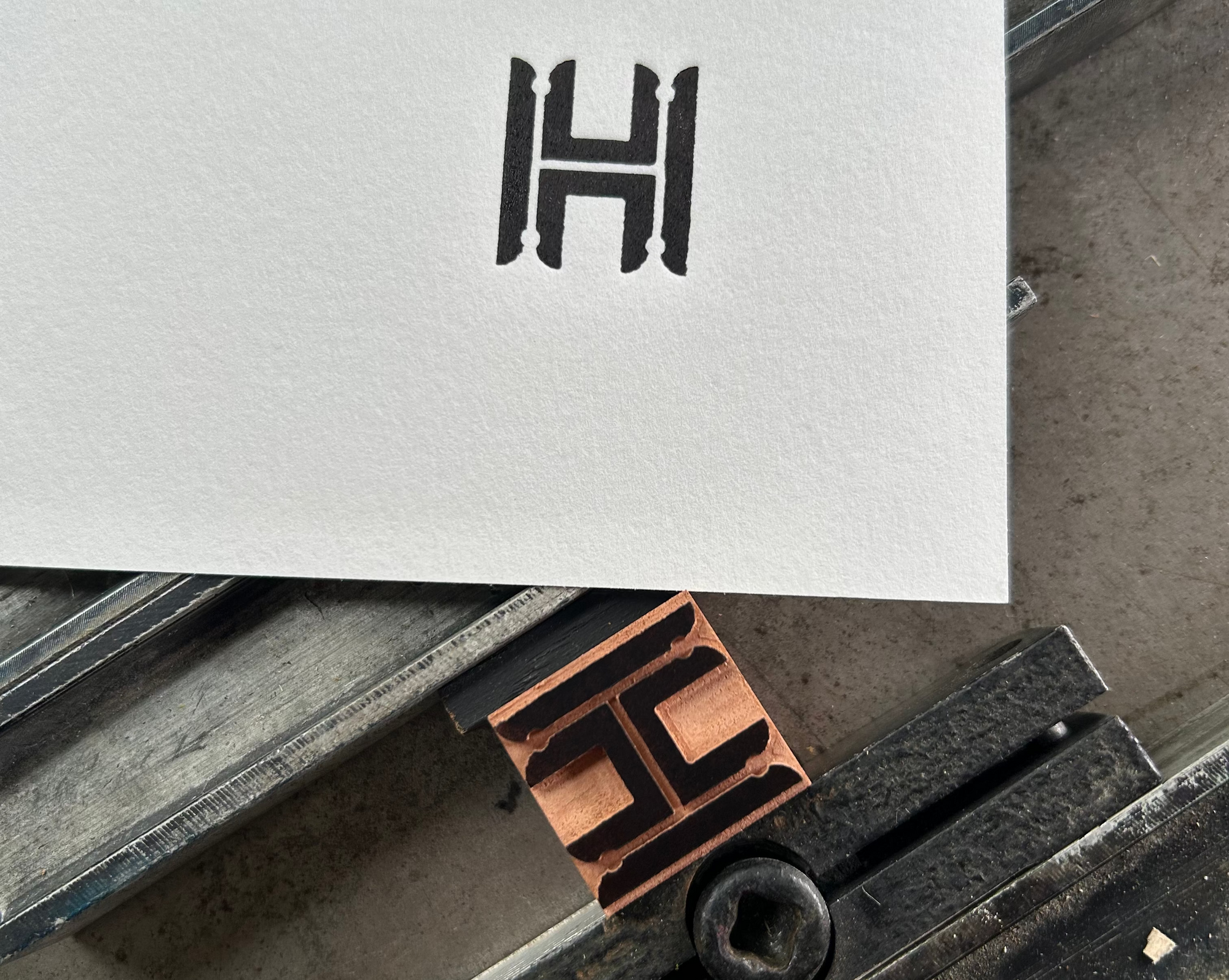 Letterpress printing block with 'H' stamp on a piece of paper